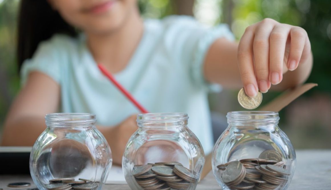 cute-asian-little-girl-playing-with-coins-making-stacks-money-kid-saving-money-into-piggy-bank-into-glass-jar-child-counting-his-saved-coins-children-learning-about-future-concept